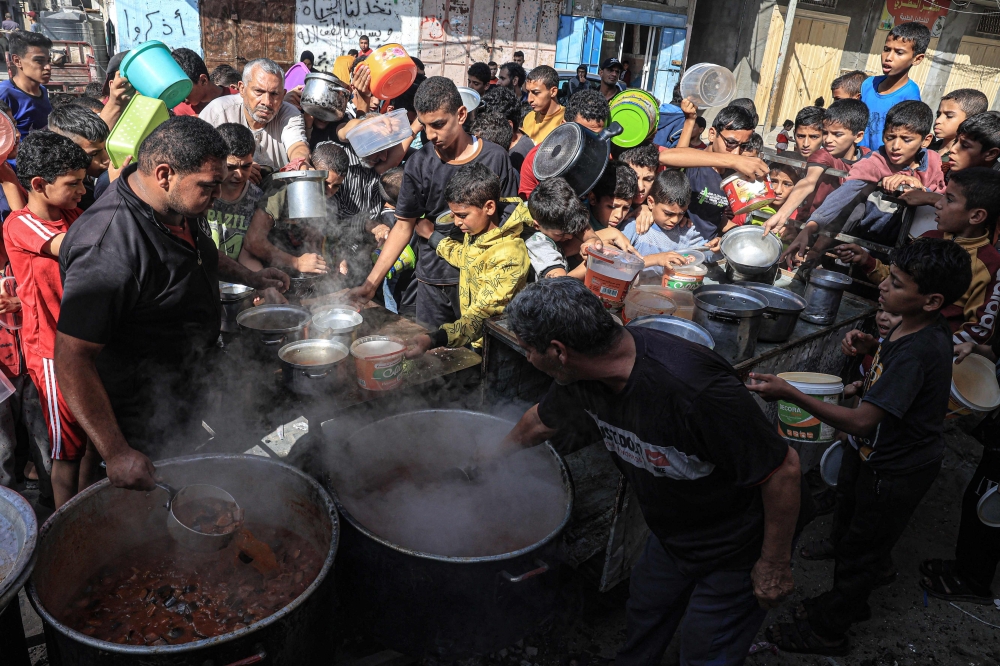 Palestinians queue for food at a makeshift charity kitchen in Rafah in the southern Gaza Strip. — AFP pic