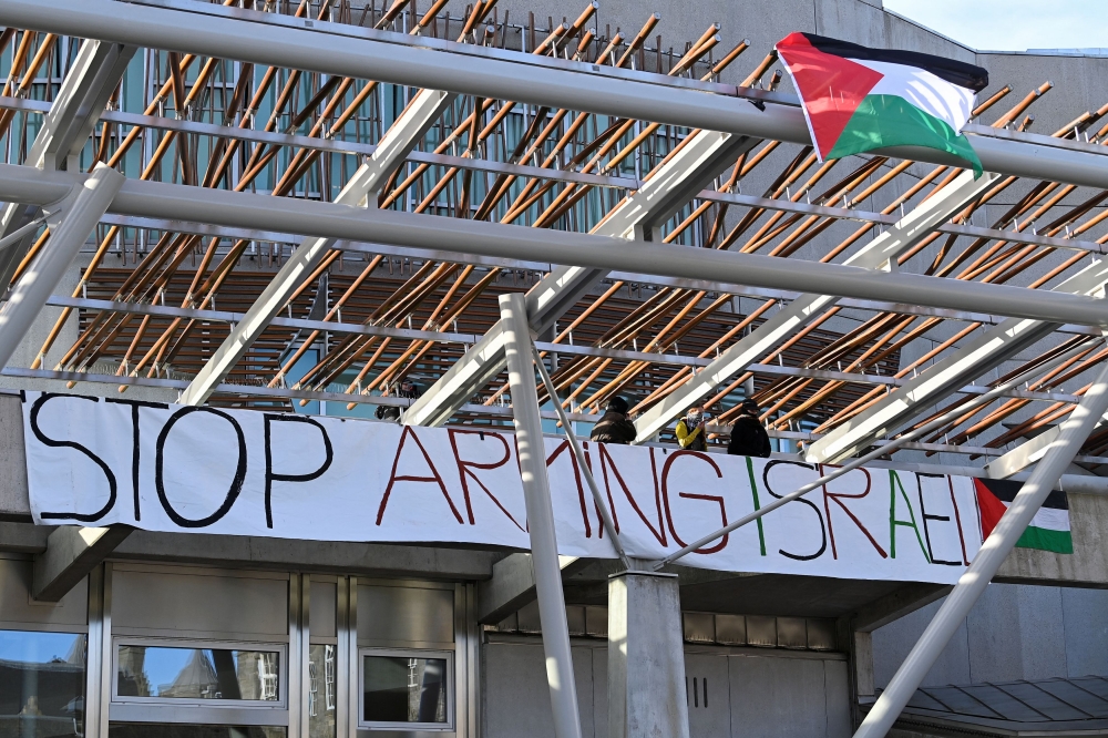 Pro-Palestinian supporters display a banner and Palestinian flags, as they occupy the roof of the Scottish Parliament, amid the ongoing conflict between Israel and Palestinian Islamist group Hamas, in Edinburgh, Britain November 9, 2023. — Reuters pic