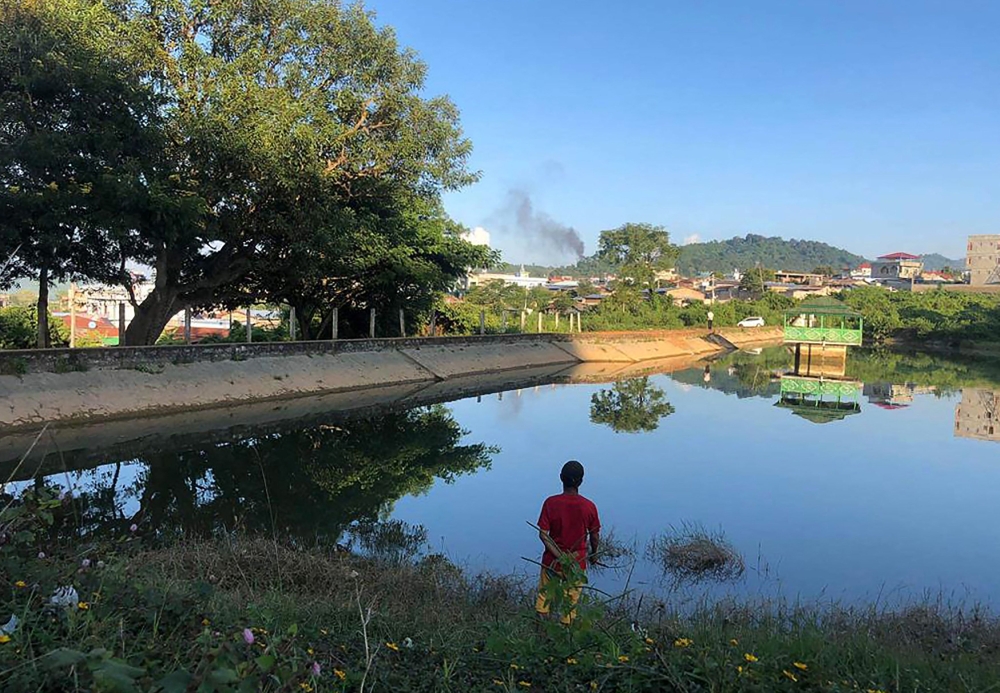 This photo taken on November 7, 2023 shows a man watching smoke rising from the direction of a Myanmar military base in Lashio township, northern Shan State. — AFP pic