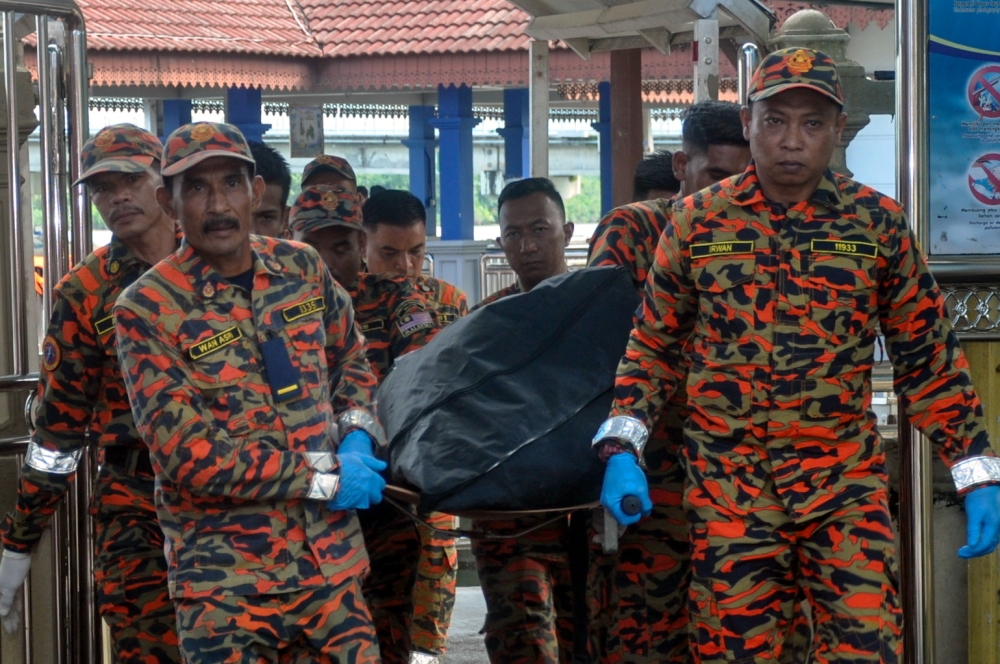 Fire and Rescue Department personnel with the body of a victim of the resort building collapse on Perhentian island upon arriving at the Kuala Besut jetty, November 10, 2023. — Bernama pic 
