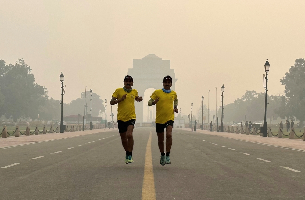 Twin brothers Shyam Babu Gupta and Ram Babu Gupta run past the India Gate memorial on a smoggy morning in New Delhi November 9, 2023. — Reuters pic