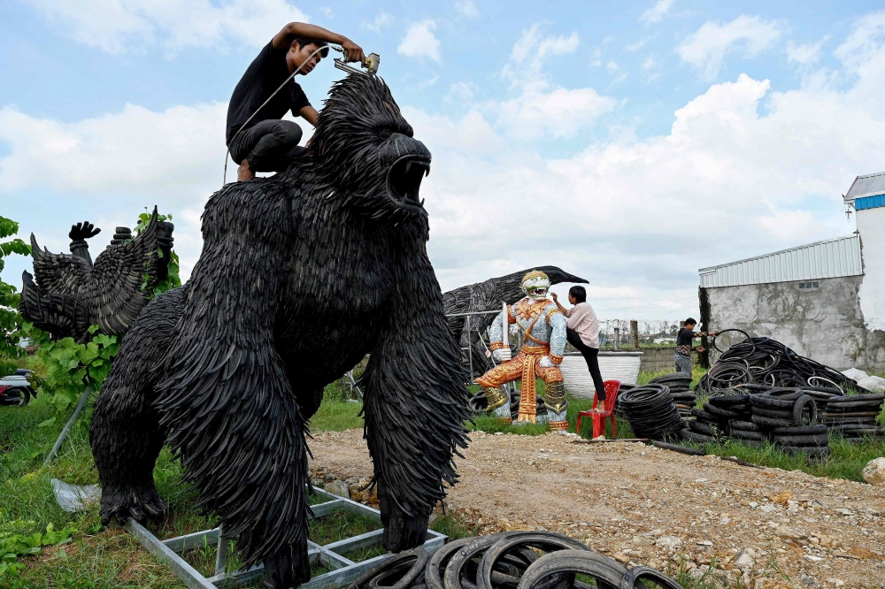 This photo taken on November 7, 2023 shows a worker fixing a King Kong statue made with old motorbike and bicycle tyres at artist Mean Tithpheap’s house in Kandal province. — AFP pic 