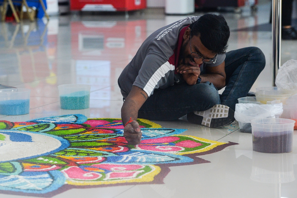 Kolam maker Sivabalan Arumugam working on a rangoli kolam for MSU Medical Centre. — Picture by Miera Zulyana. 