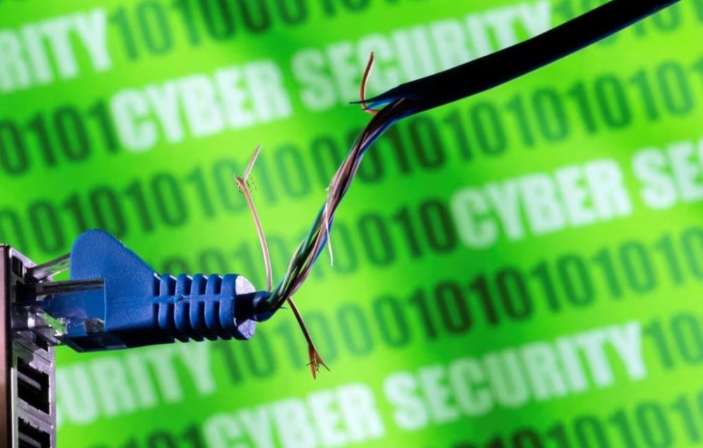 Broken Ethernet cable is seen in front of binary code and words ‘cyber security’ in this illustration taken March 8, 2022. — Reuters pic