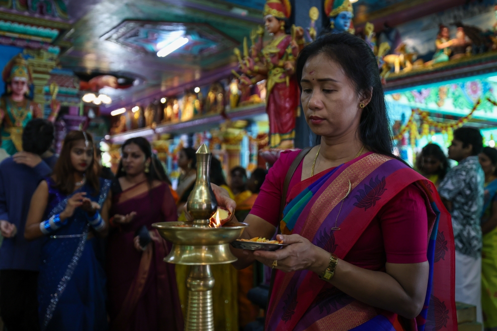 A devotee lights a vilakku or tradition lamp while performing prayers in conjunction with Deepavali at the Arulmigu Karumariamman temple in Butterworth. — Bernama pic