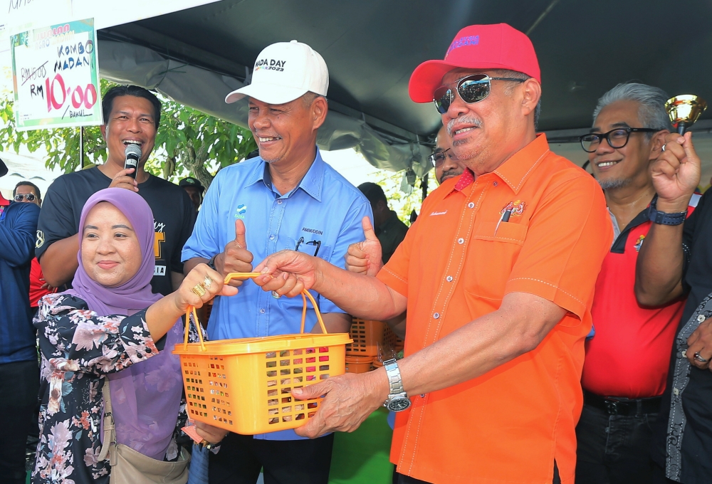 Agriculture and Food Security Minister Datuk Seri Mohamad Sabu presents a Madani food basket sold for RM10 to visitors at the Rahmah Sales booths, in conjunction with the National Farmers, Breeders and Fishermen’s Day  2023, at the Dataran Bulatan Sultan Azlan Shah in Ipoh November 12, 2023. — Bernama pic
