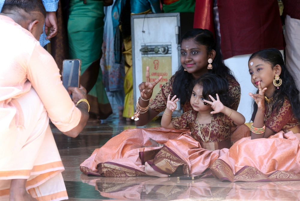 Sujes Kumar takes a picture of daughters Kayshana, Perdiba and Vamika during a visit to the Sri Maha Mariamman Devasthanam Temple in Alor Setar during Deepavali November 12, 2023. — Bernama pic