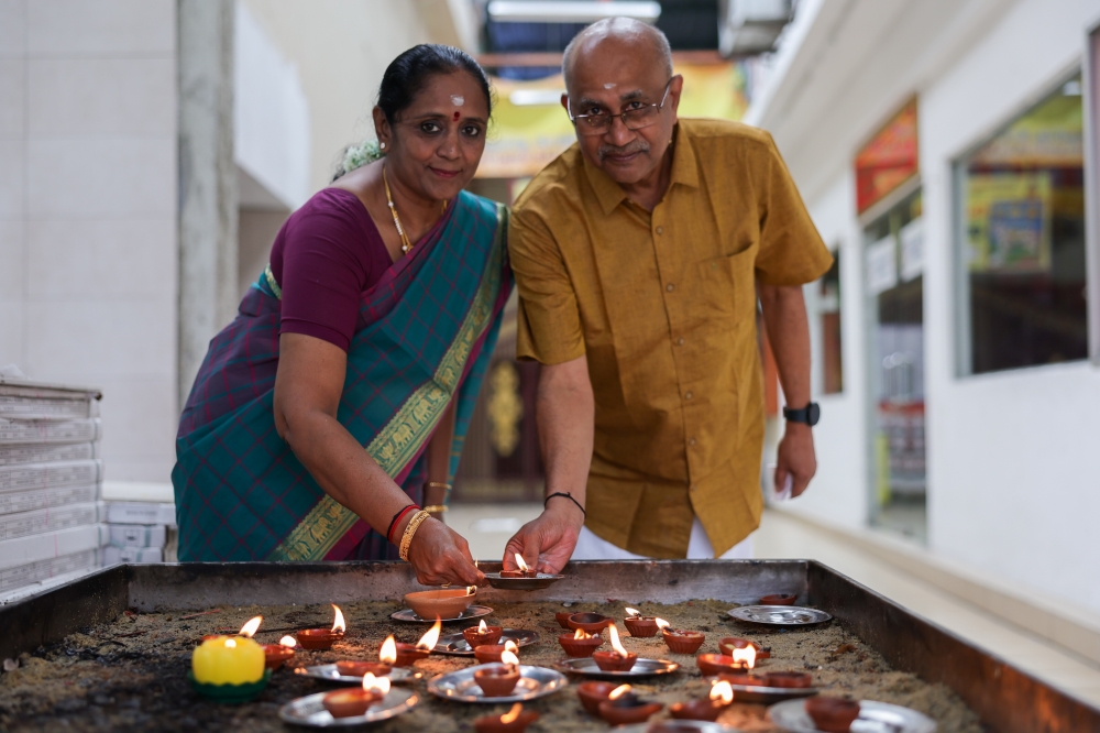 Narayanan, 66, (right) and his wife Indar, 62, light a vilakku or tradition lamp while performing prayers in conjunction with Deepavali at the Arulmigu Rajamariamman Devasthanam Temple in Johor Baru November 12, 2023. — Bernama pic