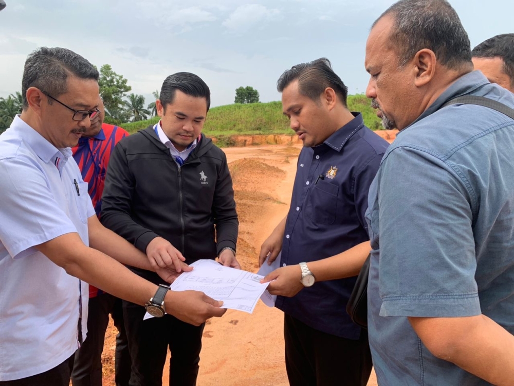 Johor Public Works, Transport and Infrastructure Committee chairman Mohamad Fazli Mohamad Salleh (second from left) looks at the development plan while visiting the relocation site for three Hindu temples in Taman Eko Flora in Johor Baru November 14, 2023. — Picture by Ben Tan
