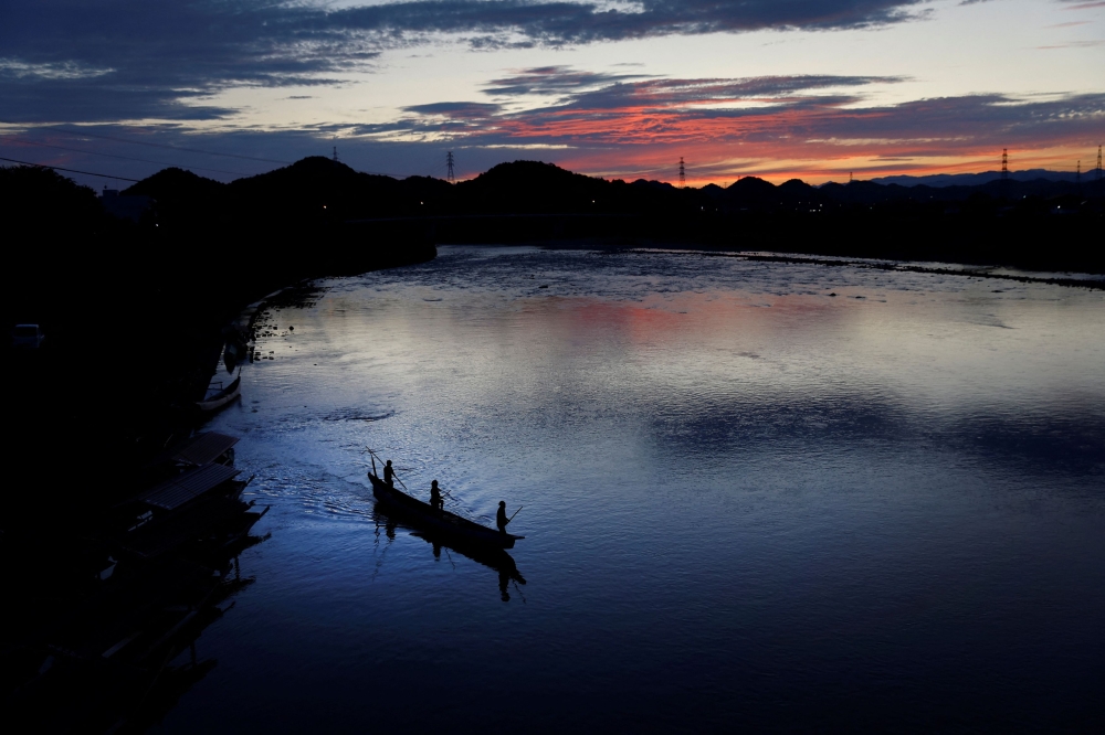 Cormorant fishing master, known as usho, Youichiro Adachi, 48, his son Toichiro, 22, and his steersman Naoki Adachi, 44, sail for cormorant fishing, known as ukai, on the Nagara River in Oze, Seki, Japan, September 9, 2023. — Reuters pic 