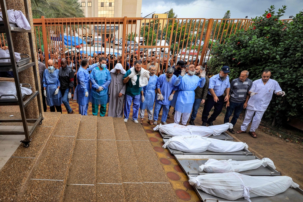 A policeman, physicians, and other men prepare to pray before some of the bodies of victims who were killed in Israeli bombardment before their burial, outside the morgue at Nasser hospital in Khan Yunis in the southern Gaza Strip on November 14, 2023 amid the ongoing battles between Israel and the Palestinian militant group Hamas. — AFP pic