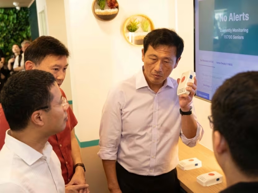 Singapore Health Minister Ong Ye Kung holding the ‘wireless alert alarm system’ at the NTUC Health Active Ageing Centre on November 16, 2023, as National Development Minister Desmond Lee and Acting Transport Minister Chee Hong Tat look on. — TODAY pic