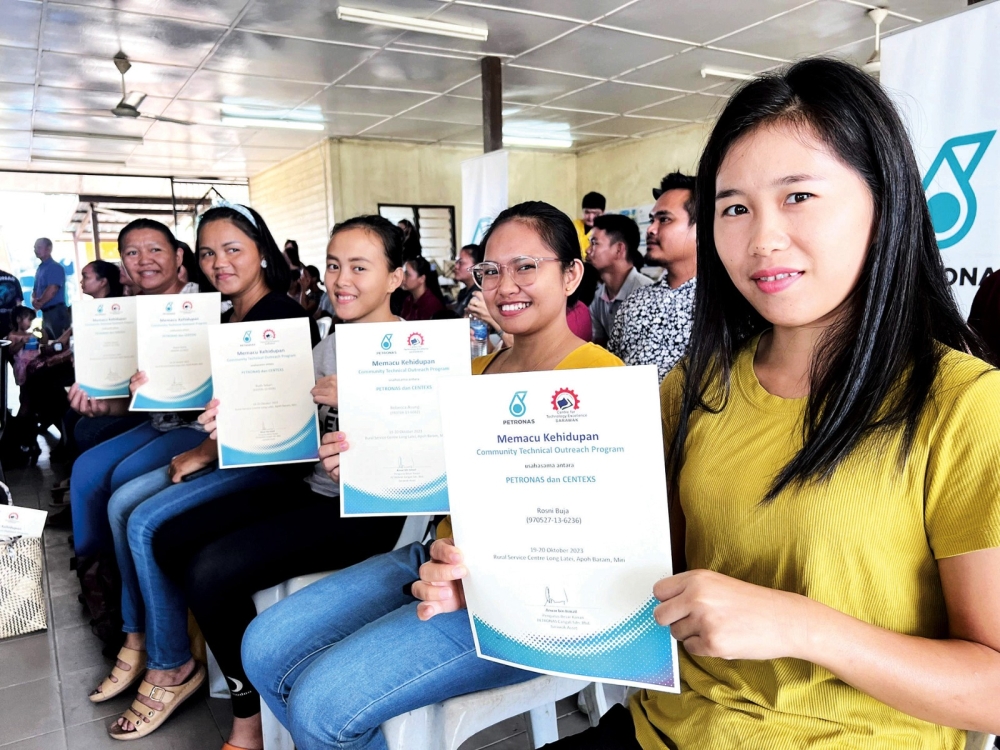 Participants celebrating completion of the course by showing their certificates. ― Borneo Post pic