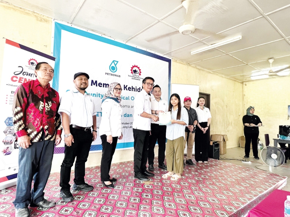 Dennis (fourth, left) presenting a certificate to a participant. Among those looking on are Isrom (third right) and Petronas Carigali Sdn Bhd ― Sarawak Assets Stakeholder Manager Management and Administration Suryani Dohan (right). ― Borneo Post pic