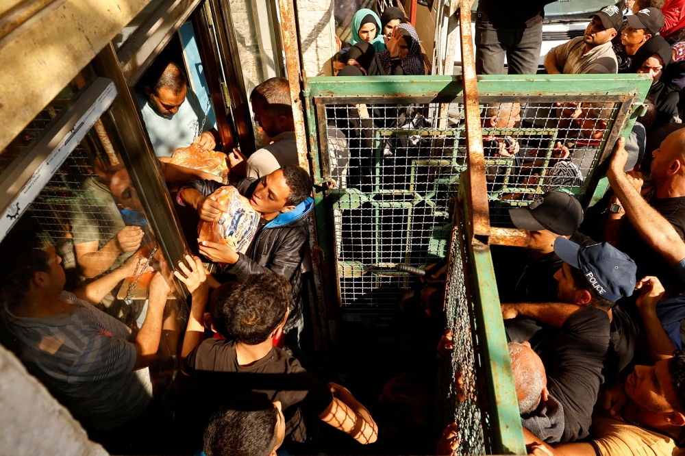 Palestinians queue as they wait to buy bread from a bakery, amid shortages of food supplies and fuel. — Reuters pic