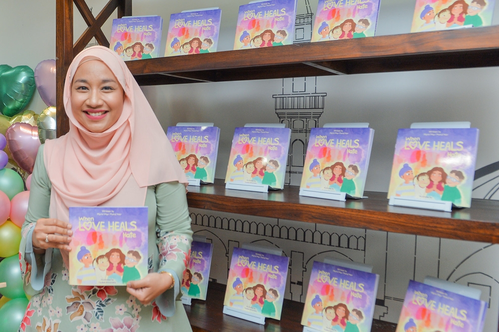 ‘When Love Heals Hate’ book author Murni Wan Mohd Nor poses with a copy of her book during its launch in Kuala Lumpur November 11, 2023. — Picture by Miera Zulyana