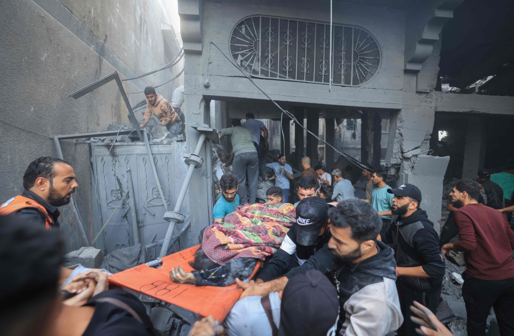 Palestinians carry an injured person pulled from the rubble following Israeli bombardment in Khan Yunis. — AFP pic