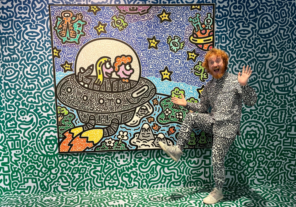 This photo taken on November 16, 2023 shows British artist Sam Cox, better known as Mr Doodle, posing for a picture with his piece ‘The Doodles Leave Earth’ at Pearl Lam Galleries in Hong Kong. — AFP pic