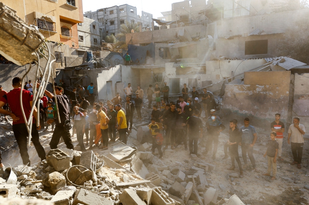 Palestinians gather to search for casualties at a site of an Israeli strike. — Reuters pic