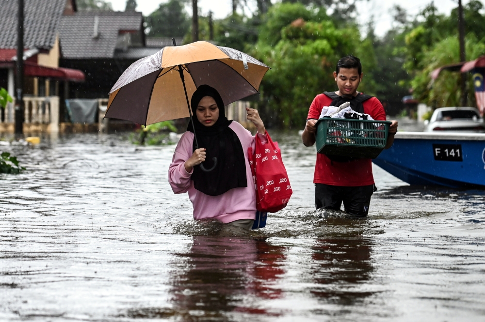 Residents of Taman Murni Permai wade in flood water as they attempt to cross a road, in Tok Jembal, Kuala Nerus November 20, 2023. — Bernama pic