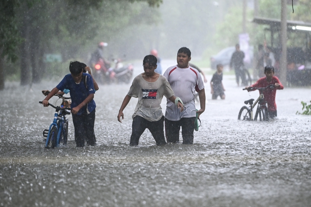 A group of children wade through the flood in the rain in Kampung Gong Baru in Kuala Terengganu, November 21, 2023. — Bernama pic 