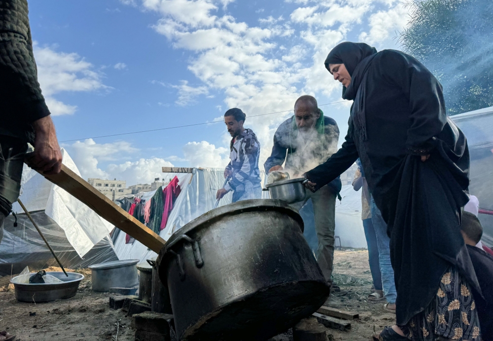 Displaced Palestinians, who fled their houses due to Israeli strikes, cook lentil soup on a rainy day at Nasser Hospital in Khan Younis in the southern Gaza Strip, November 20, 2023.  — Reuters pic
