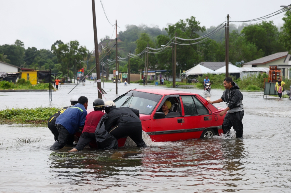 A group of men help push a car that had fallen into a drain after the road was flooded due to heavy rain for the past few days in Kampung Alor Surau Panjang, Kuala Terengganu, November 21, 2023. — Bernama pic 