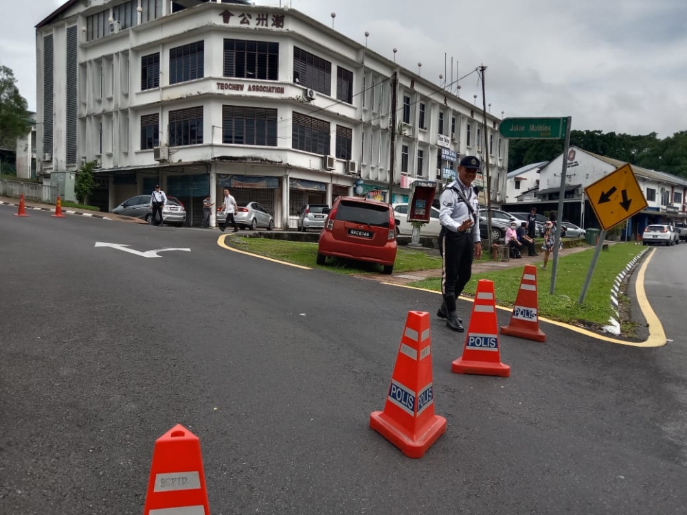 A policeman stops vehicles from going up Jalan Mathies, which leads to the school. — Borneo Post Online pic