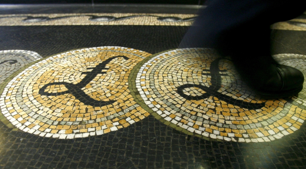 An employee is seen walking over a mosaic of pound sterling symbols set in the floor of the front hall of the Bank of England in London, in this March 25, 2008 file photograph. — Reuters pic
