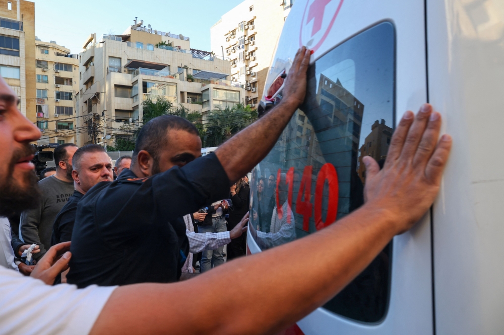 Journalists and colleagues mourn as ambulances carrying the bodies of two journalists of Lebanon-based Al Mayadeen TV channel, killed in an Israeli strike earlier in Tair Harfa, arrive for a last visit outside the channel's building in Beirut on November 21, 2023. — AFP pic