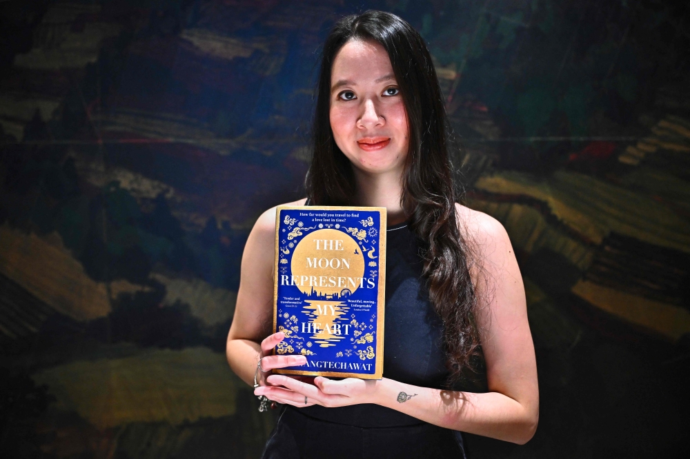 This photo taken on October 17, 2023 shows Thai author Pim Wangtechawat holding a copy of her debut novel 