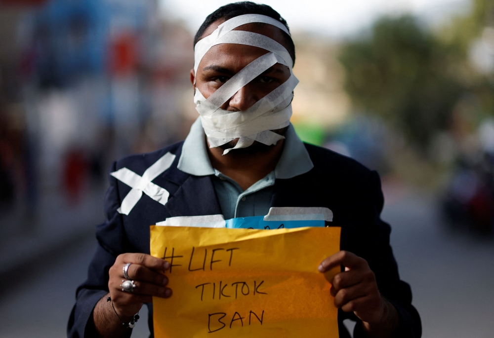 Ashish Dangi, whose face is wrapped around with tape, holds a placard as he takes part in a protest against the ban on TikTok in Kathmandu, Nepal November 18, 2023. — Reuters pic