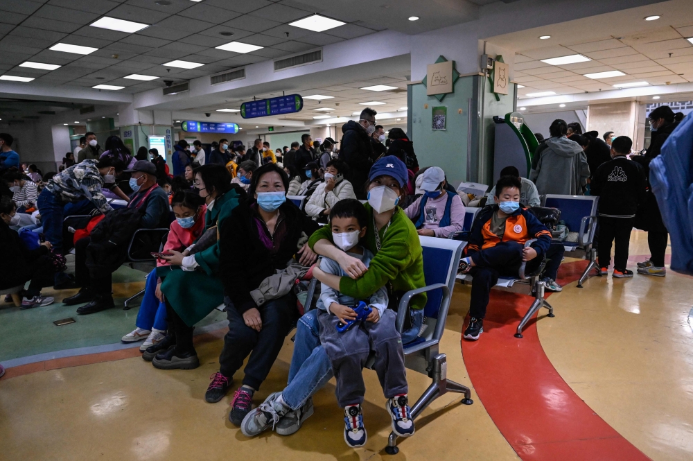 Children and their parents wait at an outpatient area at a children hospital in Beijing on November 23, 2023. — AFP pic