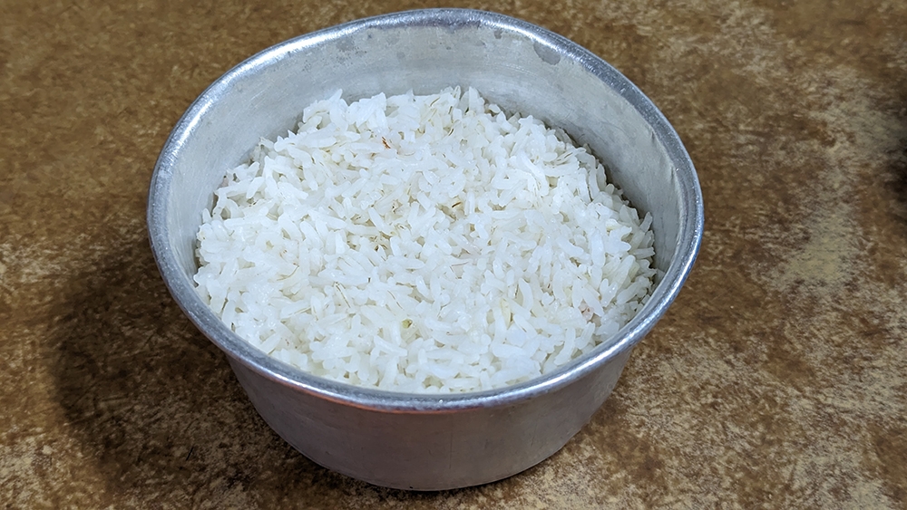 Here, rice is steamed in a large metal bowl.