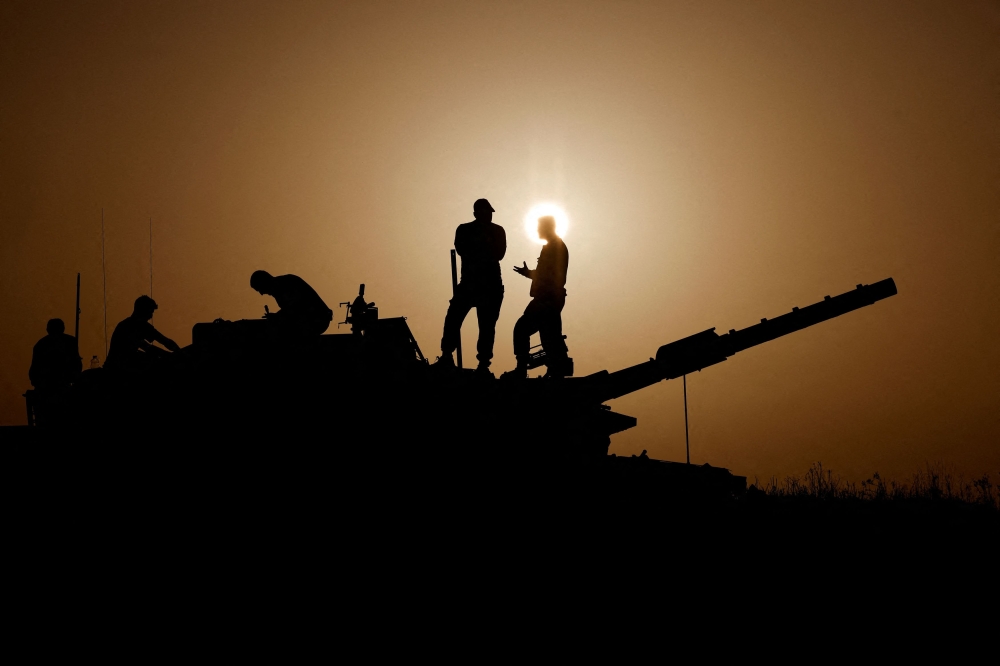 Israeli soldiers stand on a tank, amid the ongoing conflict between Israel and the Palestinian group Hamas, near Israel's border with Gaza in southern Israel, November 23, 2023. — Reuters pic
