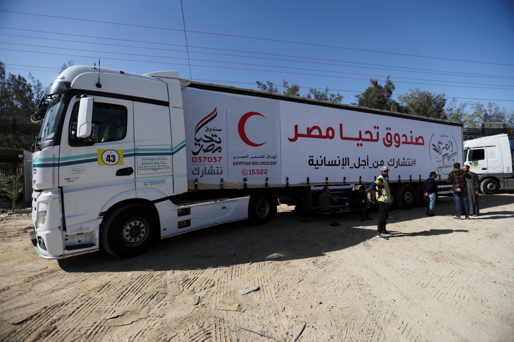 People stand near aid trucks that arrived at the Rafah border crossing with Egypt during a temporary truce between Hamas and Israel, in Rafah in the southern Gaza Strip November 24, 2023. — Reuters pic