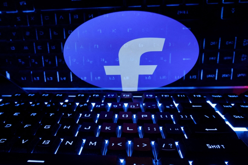 A keyboard is placed in front of a displayed Facebook logo in this illustration taken February 21, 2023. — Reuters pic