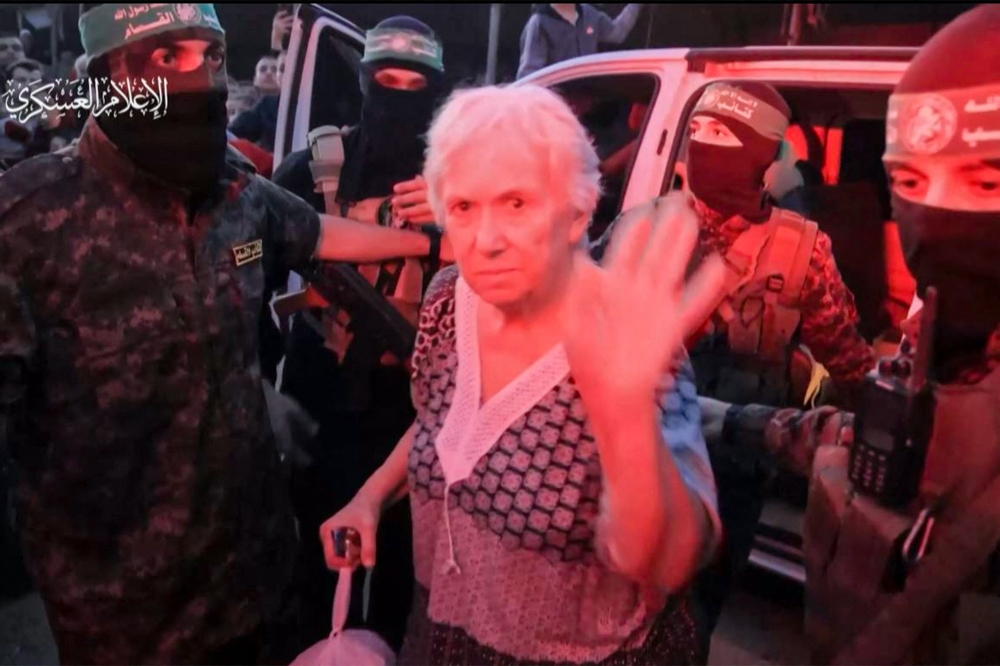 An image grab from a handout video released by the Hamas Media Office shows a hostage waving next to members of its Al-Qassam Brigades before being handed over to officials from the International Committee of the Red Cross in Gaza on November 24, 2023, ahead of her transfer to Israel. — AFP pic