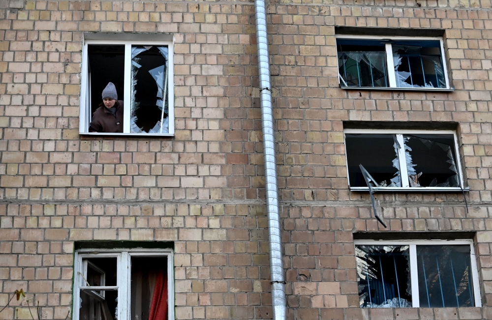 An inhabitant looks out from the broken window of her flat after the explosion of a downed Russian drone in a yard among residential buildings in Kyiv on November 25, 2023, amid the Russian invasion of Ukraine. — AFP pic