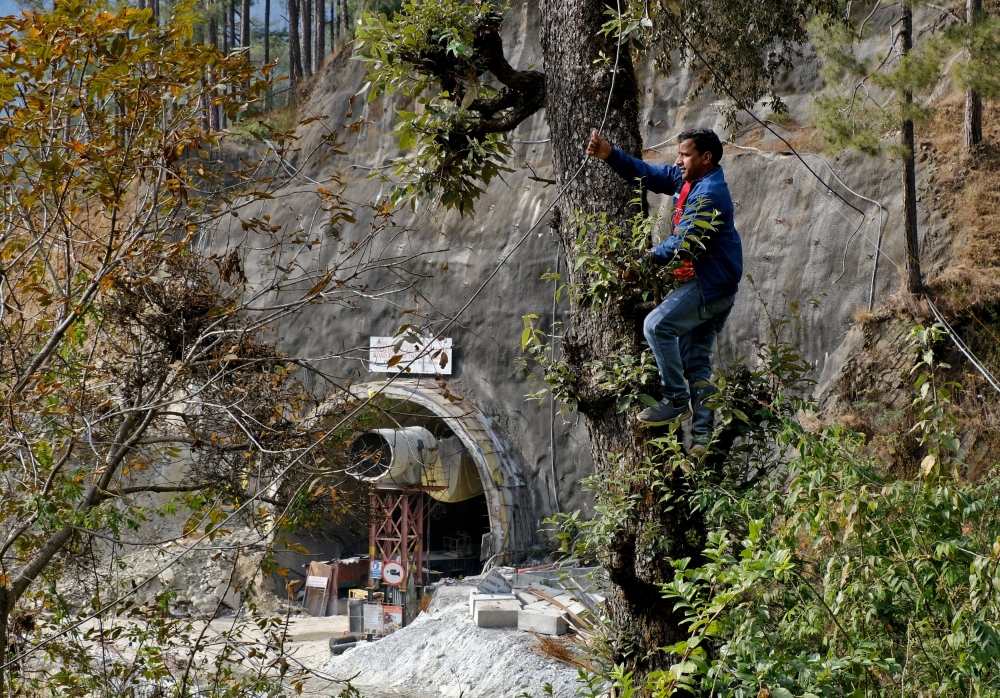 A man climbs a tree to lay a cable outside a tunnel where workers are trapped after the tunnel collapsed in Uttarkashi in the northern state of Uttarakhand, India, November 25, 2023. — Reuters pic