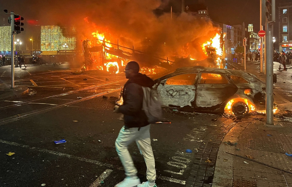 File photo of flames rising from the car and a bus, set alight at the junction of Bachelors Walk and the O’Connell Bridge, in Dublin on November 23, 2023, as people took to the streets following the stabbings earlier in the day. — AFP pic