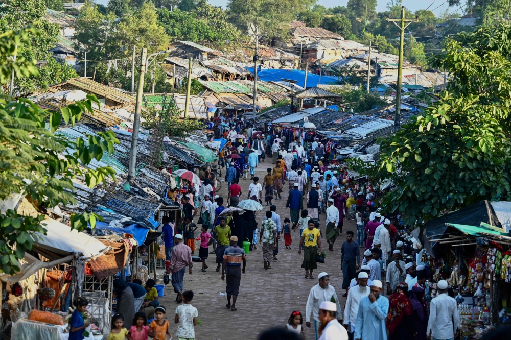 Rohingya refugees shop at a market place in Balukhali refugee camp in Ukhia on November 25, 2023. — AFP pic