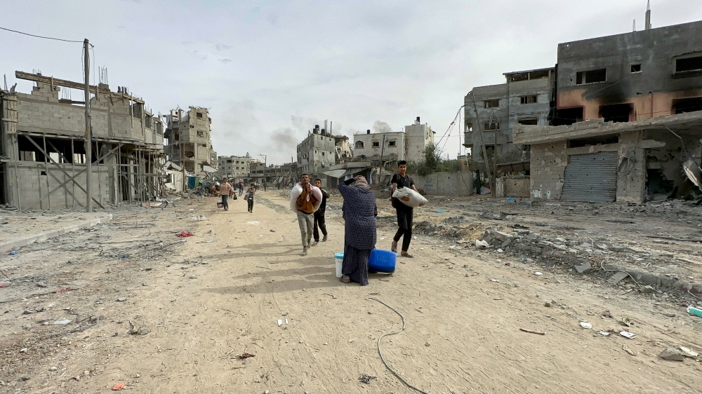Palestinians walk past houses damaged by Israeli strikes during the conflict, amid a temporary truce between Israel and Hamas, in the northern Gaza Strip, November 25, 2023. — Reuters pic
