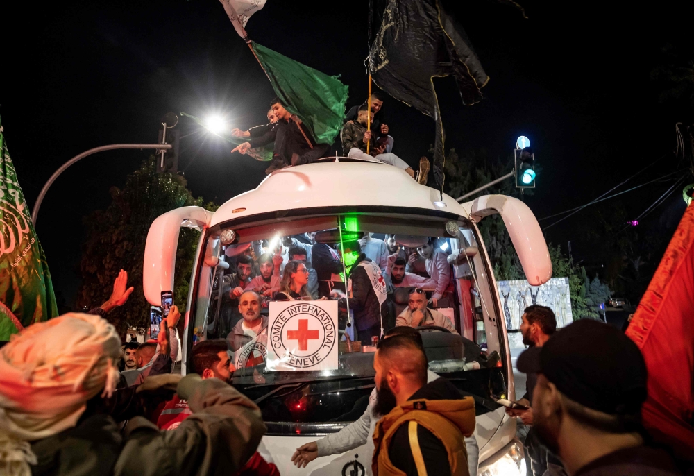 A crowd surrounds a Red Cross bus carrying Palestinian prisoners released from Israeli jails in exchange for hostages released by Hamas. — AFP pic