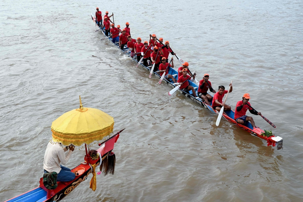 A Cambodian man prays as participants row their dragon boat during a rehearsal for the Cambodian Water Festival on the Tonle Sap river in Phnom Penh on November 26, 2023. — AFP pic