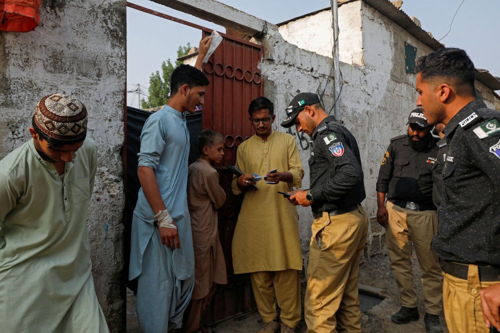 Police officers, along with workers from the National Database and Registration Authority (NADRA), check the identity cards of Afghan citizens during a door-to-door search and verification drive for undocumented Afghan nationals, in an Afghan Camp on the outskirts of Karachi, Pakistan, November 21, 2023. — Reuters pic