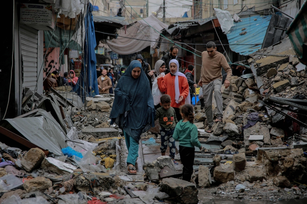 Palestinians walk amid debris of buildings hit in Israeli strikes, near Al-Zawiya market in Gaza City on November 27, 2023, on the fourth day of a truce in fighting between Israel and Hamas. — AFP pic