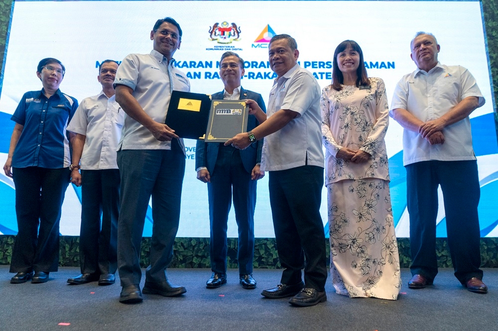 Communications and Digital Minister Fahmi Fadzil (centre) witnessed the exchange this afternoon at the Putrajaya International Convention Centre. — Picture by Shafwan Zaidon