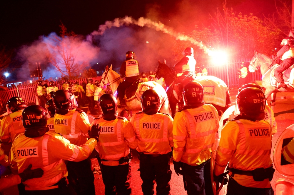Legia Warsaw fans let off flares as they clash with police officers outside the stadium before the match. — Reuters pic