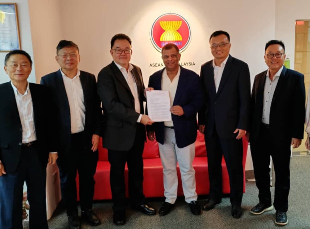 Sarawak Australia Business Chamber (SABC) president Rodger Chan (third left) presents SABC profile to AirAsia chief executive officer Tan Sri Tony Fernandes while other members look on during the courtesy call. — Borneo Post pic 